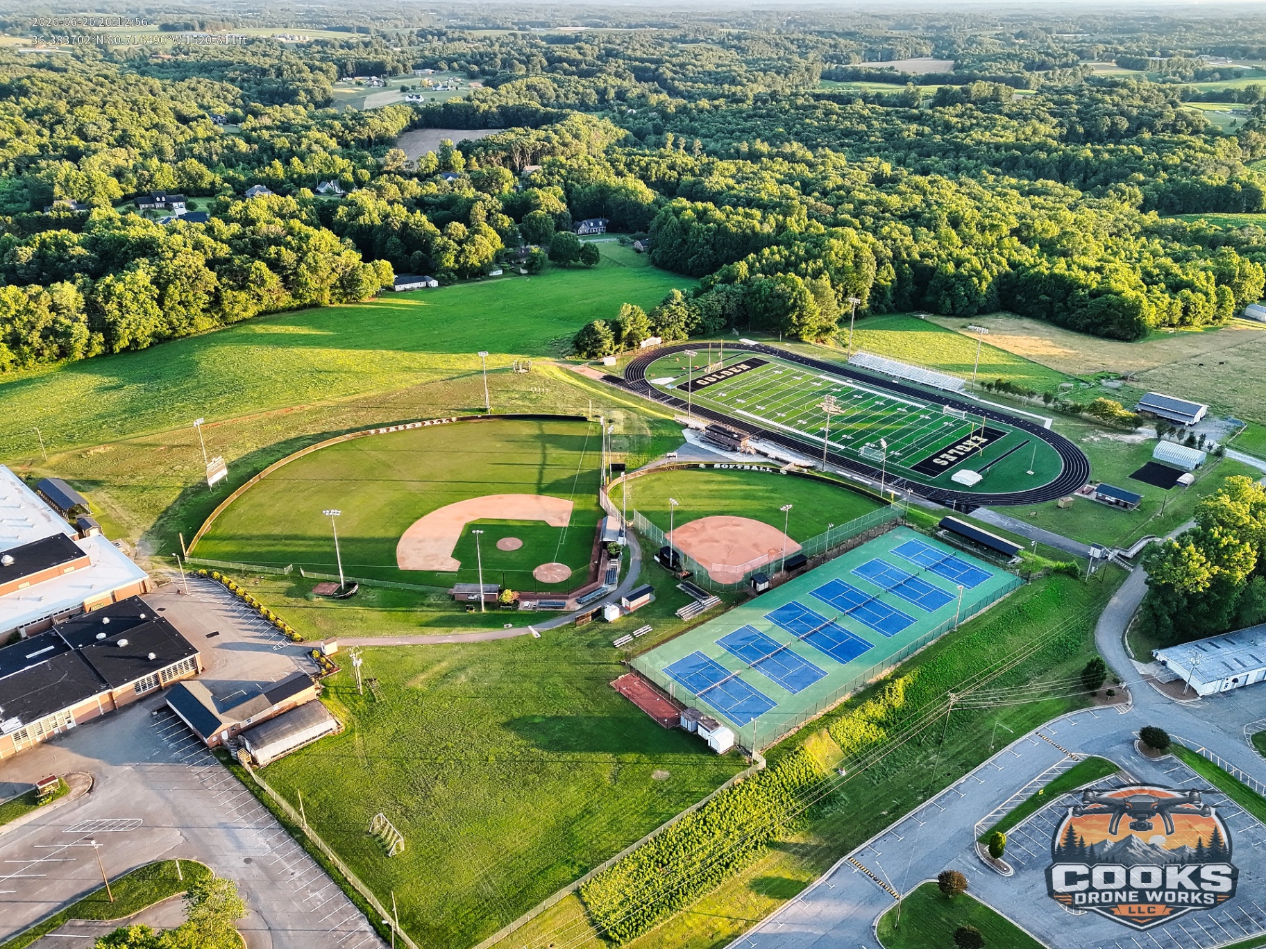 Aerial view of school athletic fields, tennis courts, and surrounding countryside