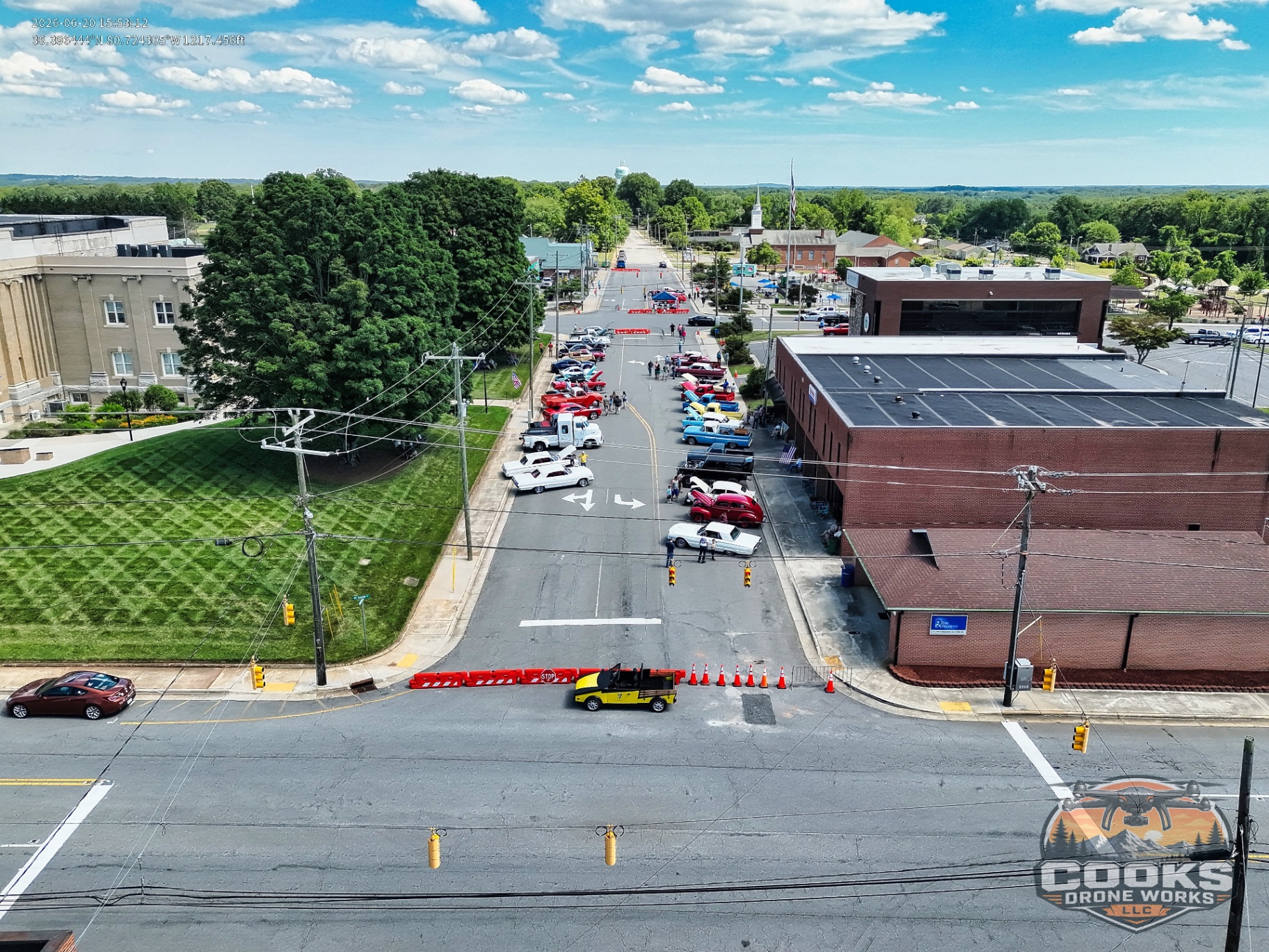 Drone view looking down a street lined with classic cars during an event